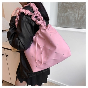 Pink pleated nylon tote bag with silver studs and ruffled shoulder strap worn by a model