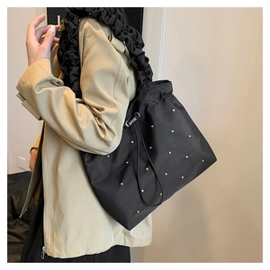 Detail of the black tote bag featuring pleated ruffled straps and sparkling rhinestones