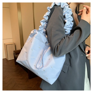 Macro detail of a light blue nylon tote bag with ruffled strap and rhinestone accents