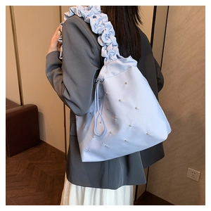 Detail of light blue pleated shoulder bag featuring silver metal rivets and ruffled strap