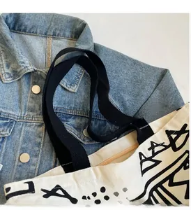 Close-up of canvas tote bag with abstract print, sturdy black straps and zipper closure