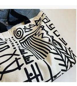 Detailed macro view of the cream canvas tote bag showing black tribal graffiti patterns