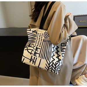 Detailed macro view of white canvas tote bag with black abstract graffiti and wide strap