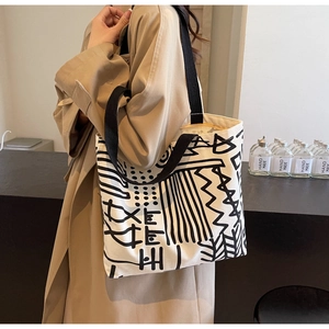 Artistic off-white canvas tote bag featuring abstract black geometric patterns and thick straps