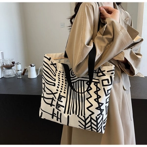 Close-up of canvas tote bag with black abstract geometric graffiti and wide strap