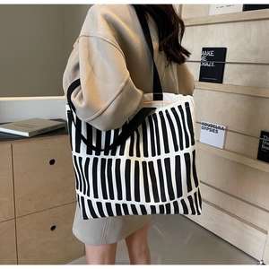 Detail of hand-painted vertical black and white stripes on a durable canvas tote bag