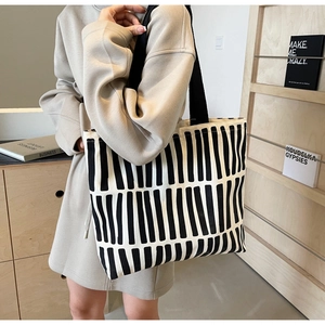 Close-up of black and white vertical striped canvas tote bag with wide black shoulder strap