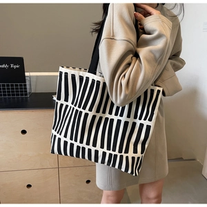 Detail of canvas tote bag showing black vertical stripes and spacious interior design