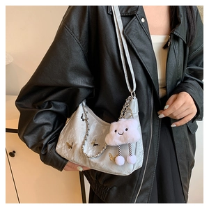 Detail of light gray textured shoulder bag with golden butterfly and plush cloud charm