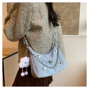 Detail of light blue hobo bag featuring silver metal butterflies and a plush cloud charm