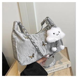 Detail of silver pleated bag with metal butterflies and a plush cloud charm