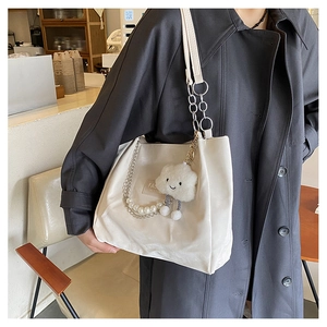 Détail du sac cabas blanc crème avec chaîne de perles et breloque nuage en peluche