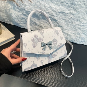 White butterfly print crossbody bag with silver bow clasp and patterned shoulder strap