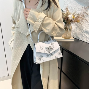 White butterfly print square handbag with silver bow lock shown in a lifestyle setting