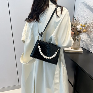 Elegant black crocodile texture shoulder bag with pearl chain shown on trench coat model
