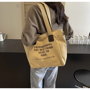 Detail view of khaki canvas tote bag with large print and leather reinforced handles