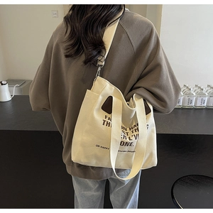 Detailed back view of a person carrying the large cream canvas tote bag in a cafe
