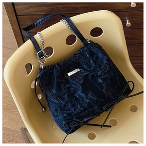 Detail der schwarzen Plissee-Tasche mit silberner Kette und Logo-Schild