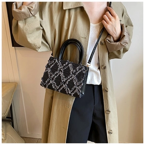 Detail of black quilted plush handbag featuring fringe texture and elegant crossbody strap