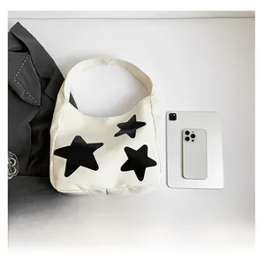 Detail shot of the white star-patterned tote bag with a tablet for size comparison