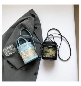 Detailed view of mini cylinder bucket bags with gold prints and metal logo plaques
