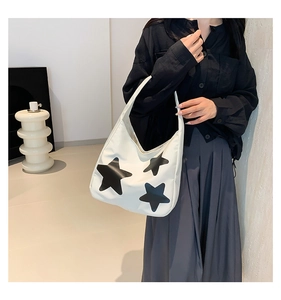 Detail van witte nylon draagtas met zwarte sterren gedragen door een model in stijl
