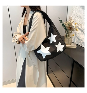Detail of black tote bag with white star appliques and wide shoulder strap