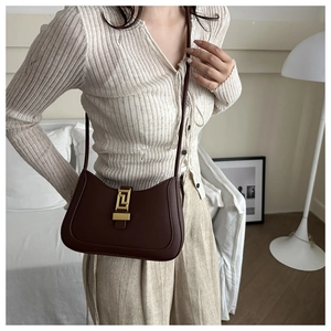 Detail view of deep brown leather underarm bag with gold geometric metal buckle closure