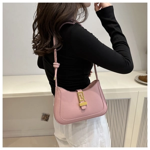 Detail view of a pink hobo bag with a gold geometric clasp worn over the shoulder