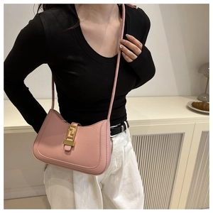 Detail of light pink moon-shaped shoulder bag featuring a gold geometric metal buckle