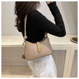 Détail du sac croissant beige montrant le fermoir doré et la bandoulière avec nœud