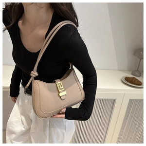 Détail du sac croissant beige avec boucle dorée porté par un mannequin de mode