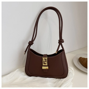 Detailed shot of dark brown moon bag with gold geometric buckle on white silk