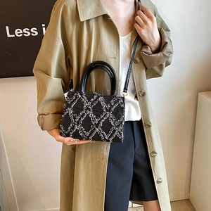 Chic black plush quilted handbag with top handles and a detachable shoulder strap