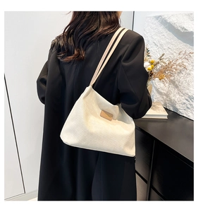 Détail de la texture du sac en velours côtelé blanc et logo en cuir sur une veste noire