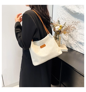 Gros plan d'un sac cabas en velours côtelé blanc avec anses en cuir marron et logo cuir