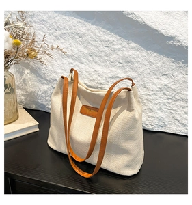 Gros plan d'un sac cabas en velours côtelé beige avec des anses marron sur bois