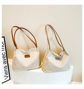 Vue détaillée de grands sacs cabas en tissu avec anses en cuir sur un socle minimaliste