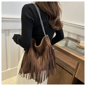 Détail d'un sac à franges en daim marron avec double chaîne en métal argenté chic