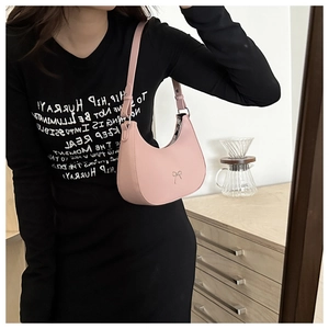 Close-up of pink leather hobo bag with silver bow detail and adjustable strap