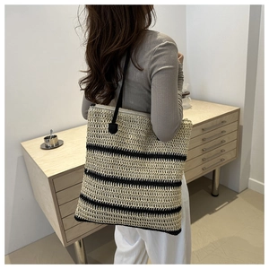 Minimalist beige and black striped woven bucket bag shown on shoulder in home setting