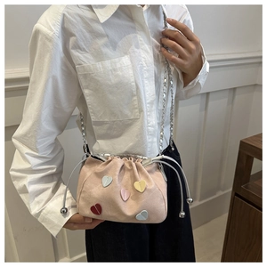 Detail of pink drawstring bucket bag with colorful heart patches and silver chain strap
