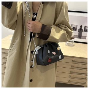 Close-up of black bucket bag with colorful heart patches and silver chain strap