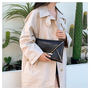 Detail of black crocodile texture envelope clutch with gold V-shape metal trim