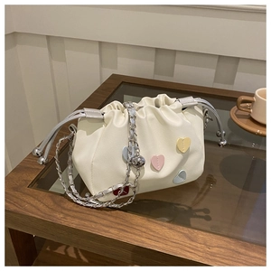 Detail of white cloud bucket bag featuring colorful heart patches and chain strap