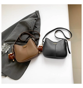 Detail view of large capacity crossbody bucket bags with bear pendants in black and brown