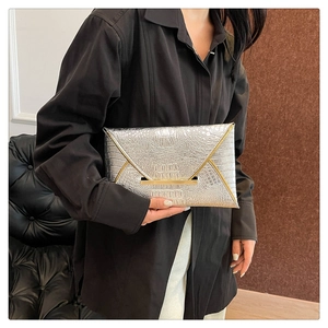 Silver crocodile embossed envelope clutch bag with gold trim held by model