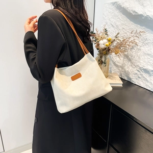 Sac fourre-tout en velours côtelé blanc avec anses en cuir marron porté à l'épaule