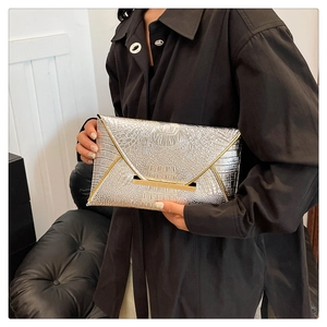 Detail of silver crocodile pattern envelope clutch bag with gold metallic trim accents