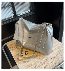 Détail du sac à rabat argenté avec bandoulière chaîne sur une surface élégante en marbre